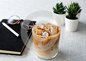 Top view cup of cold coffee with notebook, pencil and the glasseson wooden table background, modern lifstye concept