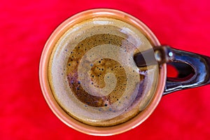 Top view of cup of creamy expresso coffee on red background