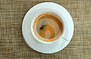 Top View of a Cup of Hot Coffee in the White Cup Served on Brown Luncheon Mat