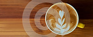 Top view of cup of latte coffee on wooden table with coppy space banner size