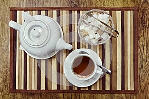 Top view of a cup of tea, teapot and sugar