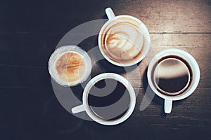 Top view of cups of different flavors hot coffee drink like flat black, cappuccino, latte, and americano on the wooden table