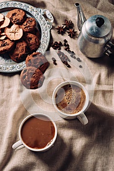 top view of cups of fresh coffee with chocolate chip cookies and vintage metal pot