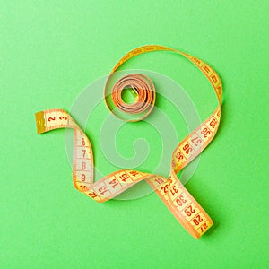 Top view of curled measuring tape as a sewing accessory on green background. Tailor concept with copy space