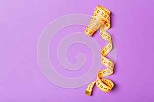 Top view of curled measuring tape as a sewing accessory on purple background. Tailor concept with copy space
