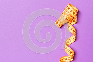 Top view of curled measuring tape as a sewing accessory on purple background. Tailor concept with copy space
