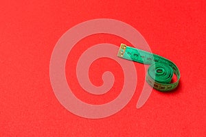 Top view of curled measuring tape as a sewing accessory on red background. Tailor concept with copy space