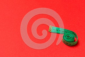 Top view of curled measuring tape as a sewing accessory on red background. Tailor concept with copy space