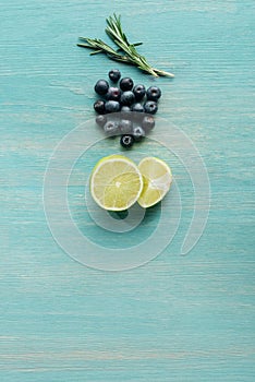 Top view of cut lemons, blueberries and rosemary on blue textured surface.