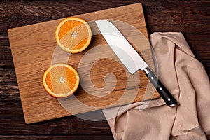 Top view of cut orange and knife on wooden board