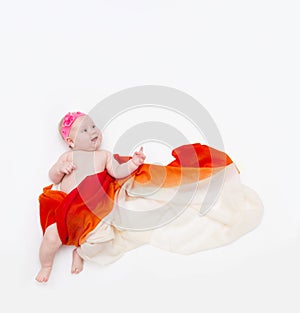 Top view of cute infant baby wrapped in a orange scarf pointing up