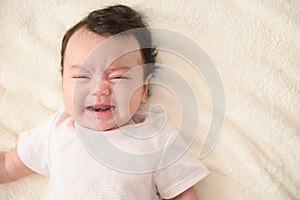 Top view of cute little Asian baby crying with copy space