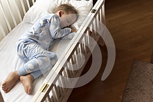 top view Cute little 2-3 years preschool baby boy kid sleeping sweetly in white crib during lunch rest time in blue