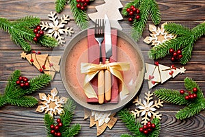 Top view of cutlery and plate on festive wooden background. New Year family dinner concept. Fir tree and Christmas decorations