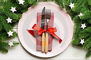 Top view of cutlery and plate on festive wooden background. New Year family dinner concept. Fir tree and Christmas decorations