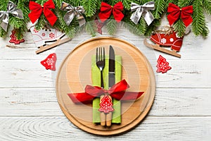 Top view of cutlery and plate on festive wooden background. New Year family dinner concept. Fir tree and Christmas decorations