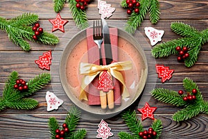 Top view of cutlery and plate on festive wooden background. New Year family dinner concept. Fir tree and Christmas decorations