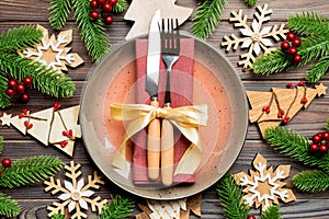 Top view of cutlery and plate on festive wooden background. New Year family dinner concept. Fir tree and Christmas decorations