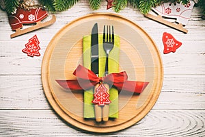 Top view of cutlery and plate on festive wooden background. New Year family dinner concept. Fir tree and Christmas decorations