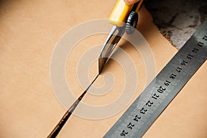 Top view of cutting tool and metal ruler while producing leather goods at table