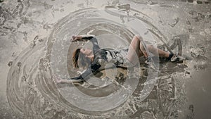 Top view. Dancer girl dressed in black body suit dance on the floor inside cloud of dust or white powder. Dancer girl