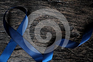 Top view of dark blue ribbon on wooden background with copy space. Colon, stomach, colorectal cancer, arthritis awareness