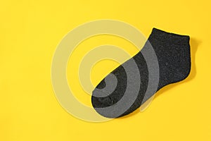 Top view of dark gray color men`s socks  on yellow background with copy space, flat lay