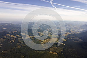 Top view of dark mountain hills covered with bare patches of cut down forest pine trees as result of deforestation