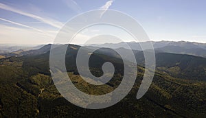 Top view of dark mountain hills covered with bare patches of cut down forest pine trees as result of deforestation