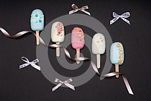 top view of decorated cake pops ice creams on black background