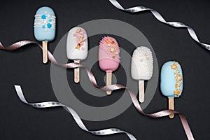 top view of decorated cake pops ice creams on black background