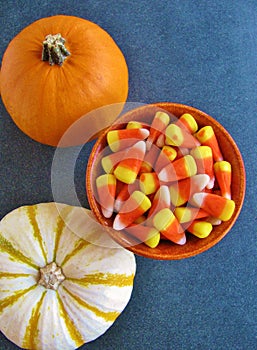 Top view of decorative Halloween pumpkins and bright orange, yellow and white candy corn, a traditional American seasonal sweet.