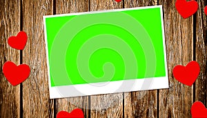 Top view of decorative red hearts with photo frame with chroma key green screen on old wood background
