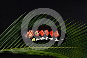 Top view of deep-fried prawns, avocado, mayonnaise and tobiko sushi isolated on black table