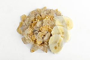 Top view of delicious corn flakes and pieces of banana on the white surface