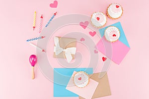 Top view of delicious cupcakes, colorful candles and hearts symbols on pink