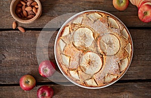 Top view of delicious fruit cake with apples and almonds on a dark wooden background