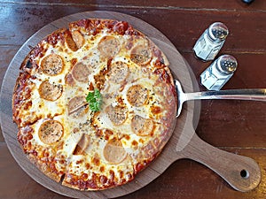 Top view of a delicious gourmet pizza with tomatoes on a wooden board