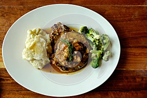 Top view of delicious grilled pork chops with mash potato and steamed green broccoli on brown wood table