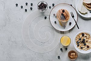 top view of delicious homemade breakfast with pancakes fruits honey and muesli on grey