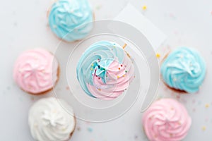 Top view of delicious pink, white and blue cupcakes with sprinkles and blank card Isolated On White.