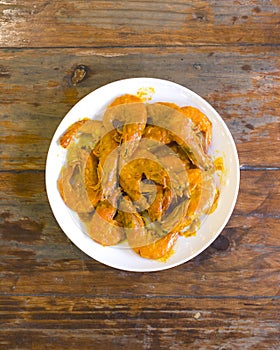 Top view of delicious Salted egg shrimp or prawns, on a white plate on a wood table