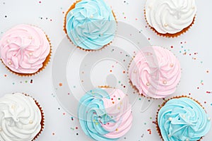 Top view of delicious white, pink and blue cupcakes with sprinkles Isolated On White.