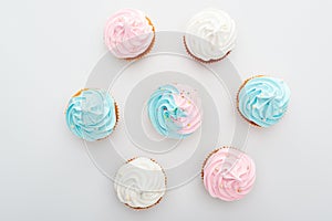 Top view of delicious white, pink and blue cupcakes with sprinkles Isolated On White.