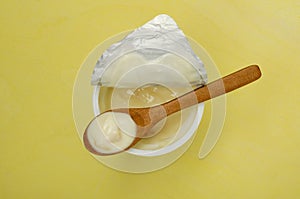 Top view of delicious yogurt with pieces of banana on the yellow background