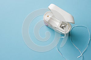 Top view of dental floss in white box on blue background