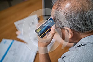 Top view of Depressed Senior Elderly male hold cradit card, feel worry about financial problem. Stressed old man look to paperwork