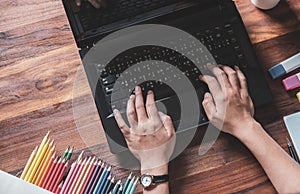 Top view.Designer in Scottish shirt, Graphic creative holding Mouse pen and working on laptop in office,Sunset background,