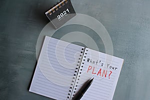 Top view of desk calendar and notebook with text WHAT`S YOUR PLAN?