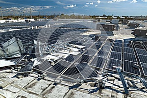 Top view of destroyed by hurricane Ian photovoltaic solar panels mounted on industrial building roof for producing green
